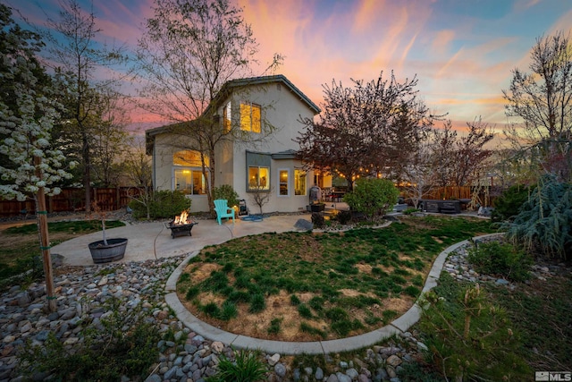 2900 Ariel Dr, Reno, NV 89523 - back of house at dusk featuring a fire pit, a patio, and stucco siding