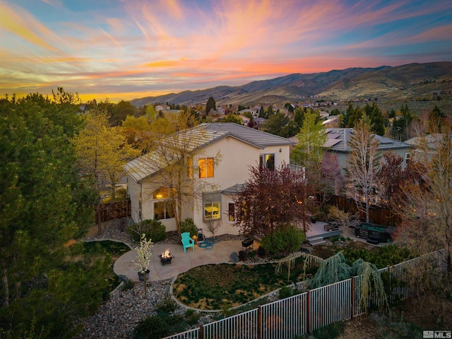2900 Ariel Dr, Reno, NV 89523 - back of house at dusk featuring a patio, stucco siding, a mountain view, and a fenced backyard