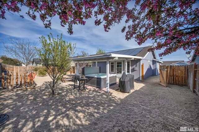 233 Jennys Ln, Fernley, NV 89408 - back of property featuring a hot tub, a fenced backyard, solar panels, and a patio