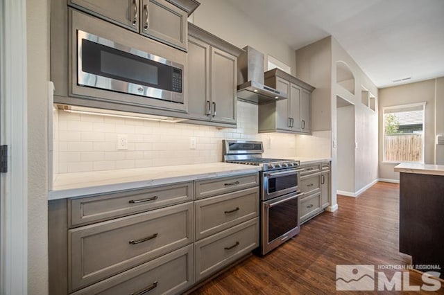 kitchen featuring wall chimney range hood, appliances with stainless steel finishes, gray cabinetry, and light countertops