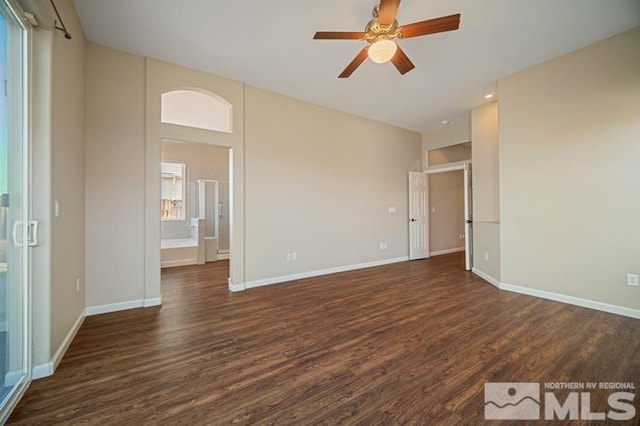 unfurnished room featuring dark wood-style flooring, a ceiling fan, and baseboards
