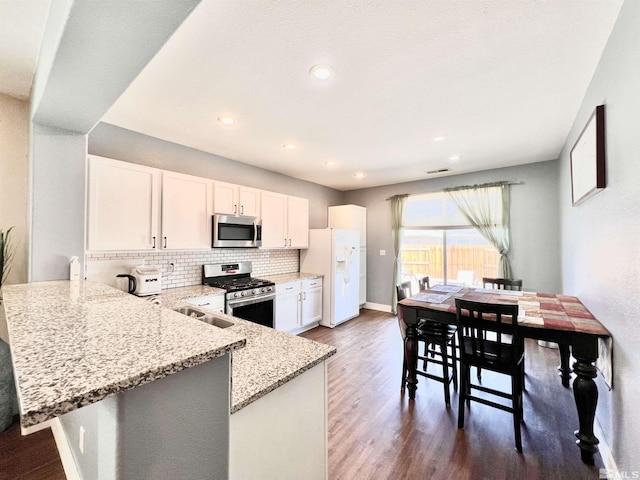 1480 Shadow Ln, Fernley, NV 89408 - kitchen featuring appliances with stainless steel finishes, light stone countertops, decorative backsplash, white cabinetry, and dark wood-style flooring