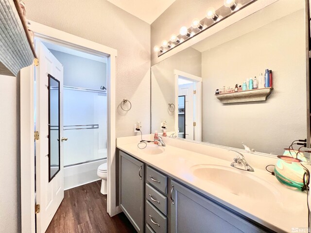 1480 Shadow Ln, Fernley, NV 89408 - bathroom featuring wood finished floors, toilet, double vanity, and bath / shower combo with glass door