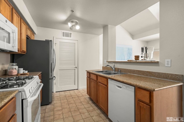 1325 S Meadows Pkwy Unit 322, Reno, NV 89521 - kitchen with white appliances, a sink, and brown cabinets