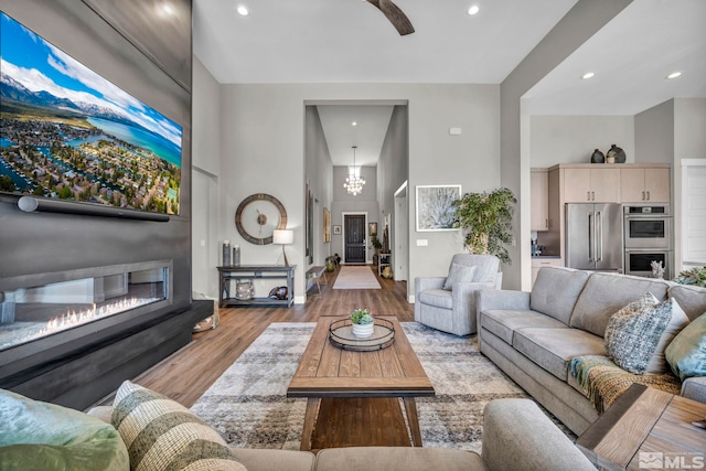 5469 Side Saddle Trl, Reno, NV 89511 - living area with a towering ceiling, light wood-type flooring, a glass covered fireplace, a chandelier, and recessed lighting
