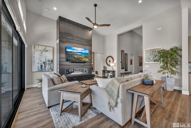 5469 Side Saddle Trl, Reno, NV 89511 - living room featuring a glass covered fireplace, high vaulted ceiling, baseboards, a ceiling fan, and wood finished floors