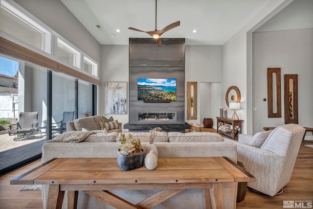 5469 Side Saddle Trl, Reno, NV 89511 - living area featuring plenty of natural light, a towering ceiling, a glass covered fireplace, wood finished floors, and ceiling fan