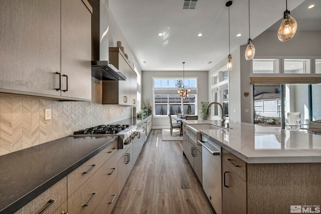 5469 Side Saddle Trl, Reno, NV 89511 - kitchen with stainless steel appliances, wall chimney exhaust hood, a sink, light wood-type flooring, and decorative backsplash