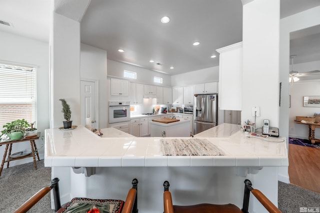 1510 Corleone Dr, Sparks, NV 89434 - kitchen with stainless steel fridge with ice dispenser, oven, a peninsula, white cabinetry, and recessed lighting