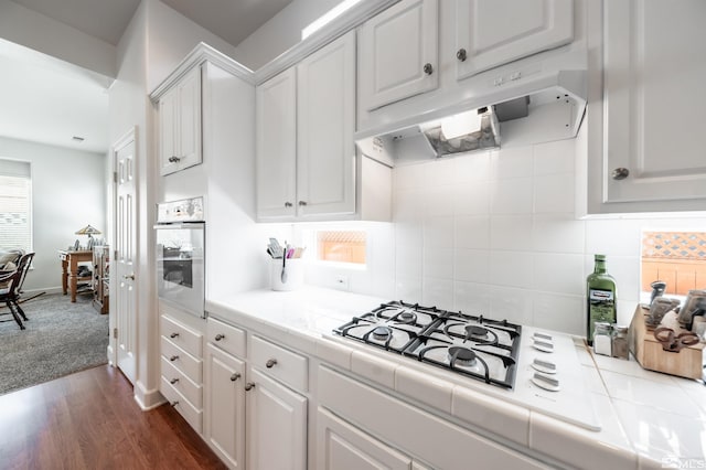 1510 Corleone Dr, Sparks, NV 89434 - kitchen with white appliances, under cabinet range hood, tile countertops, white cabinets, and tasteful backsplash