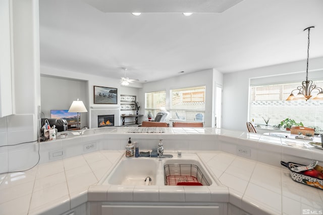 1510 Corleone Dr, Sparks, NV 89434 - kitchen featuring tile counters, open floor plan, a glass covered fireplace, a ceiling fan, and a sink