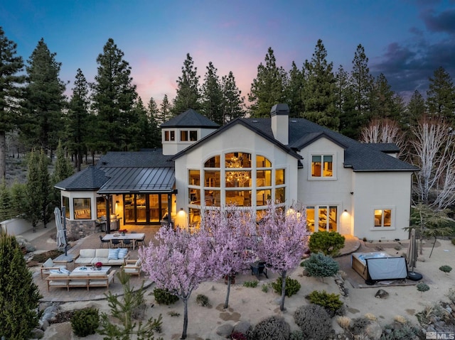 120 W Willis Ln, Reno, NV 89511 - back of property at dusk featuring an outdoor living space, a chimney, a patio, stucco siding, and a standing seam roof