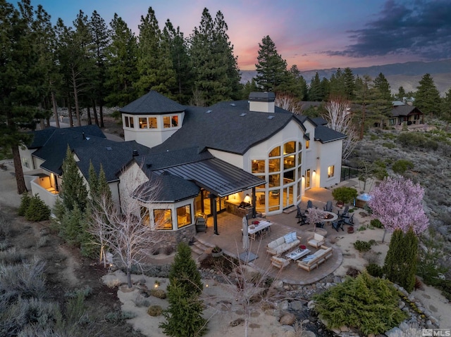 120 W Willis Ln, Reno, NV 89511 - rear view of house with a patio area, stucco siding, a chimney, roof with shingles, and stone siding