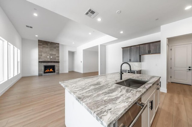 3237 Amaretto Way Unit Cinmon 64, Sparks, NV 89441 - kitchen with a sink, light wood-type flooring, light stone counters, a kitchen island with sink, and a fireplace