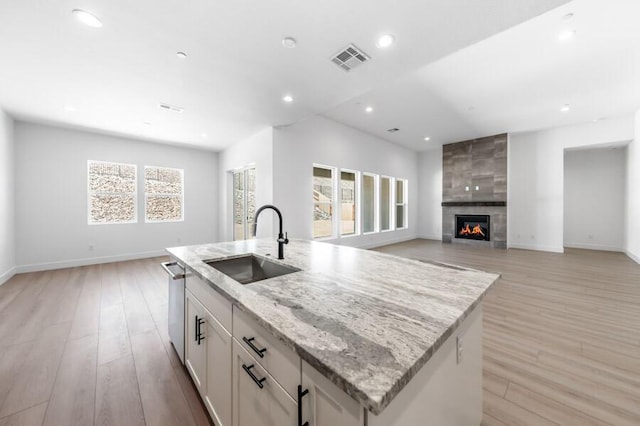 3237 Amaretto Way Unit Cinmon 64, Sparks, NV 89441 - kitchen featuring a sink, a center island with sink, stainless steel dishwasher, light stone countertops, and baseboards