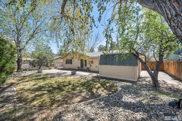 1308 Fremont, Carson City, NV 89701 - back of house with a fenced backyard, a patio area, a storage unit, an outdoor structure, and roof with shingles