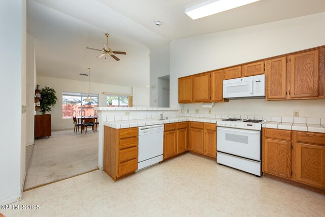 1774 Evergreen Ct, Minden, NV 89423 - kitchen with white appliances, brown cabinets, a peninsula, ceiling fan, and high vaulted ceiling