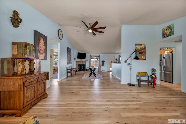 534 Dutch Oven Ct, Fernley, NV 89408 - living area featuring a ceiling fan, light wood-type flooring, a tile fireplace, baseboards, and vaulted ceiling