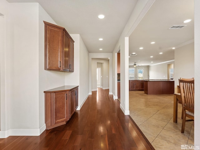 hall featuring baseboards, recessed lighting, and wood finished floors