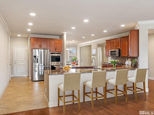 kitchen featuring appliances with stainless steel finishes, a sink, crown molding, a peninsula, and decorative backsplash