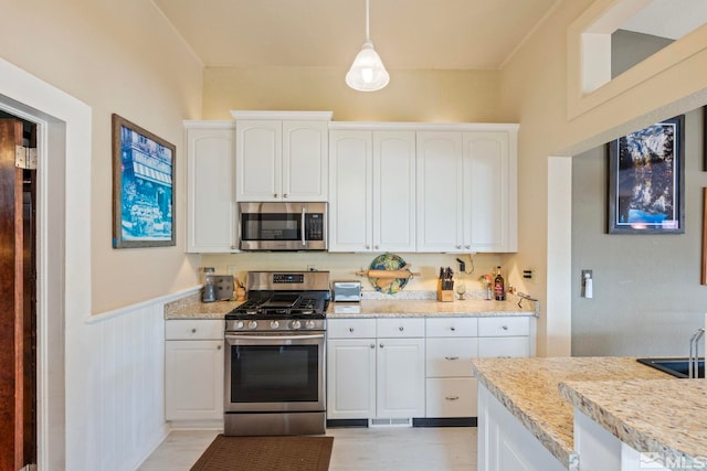 2640 Emily St, Reno, NV 89503 - kitchen featuring appliances with stainless steel finishes, white cabinetry, a wainscoted wall, and decorative light fixtures