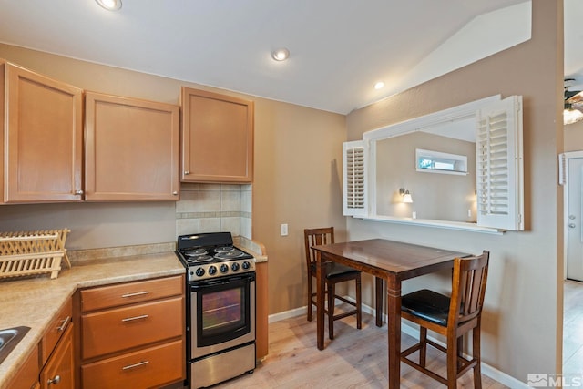 2640 Emily St, Reno, NV 89503 - kitchen with stainless steel range, light wood finished floors, light countertops, vaulted ceiling, and decorative backsplash