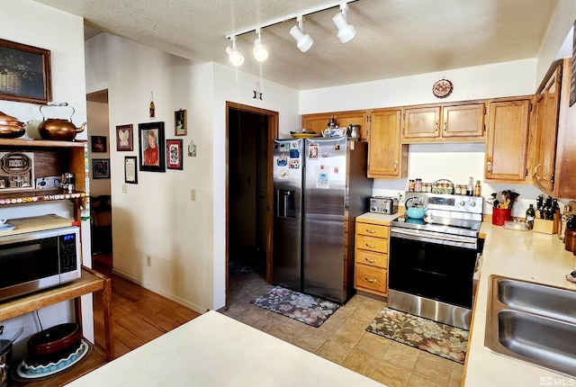 495 Burntwood St, Fallon, NV 89406 - kitchen with appliances with stainless steel finishes, a sink, light countertops, track lighting, and brown cabinetry