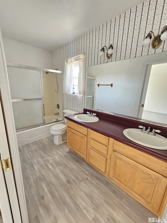 7335 Starhill Way, Sparks, NV 89436 - full bath featuring enclosed tub / shower combo, double vanity, wood finished floors, wallpapered walls, and toilet