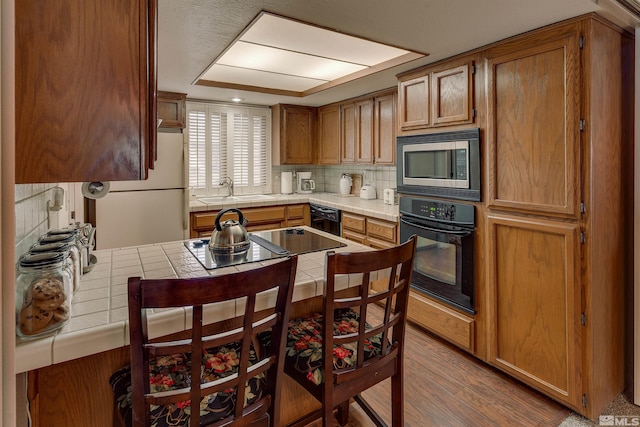 2103 Chicory Way, Reno, NV 89509 - kitchen featuring black appliances, tile counters, backsplash, and brown cabinets