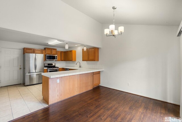 4251 Furgerson Ranch Rd, Carson City, NV 89701 - kitchen with appliances with stainless steel finishes, a peninsula, a chandelier, brown cabinetry, and a sink