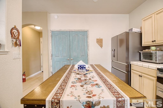 2078 Tivoli, Sparks, NV 89434 - kitchen with tile counters, stainless steel fridge with ice dispenser, arched walkways, light wood-type flooring, and cream cabinetry