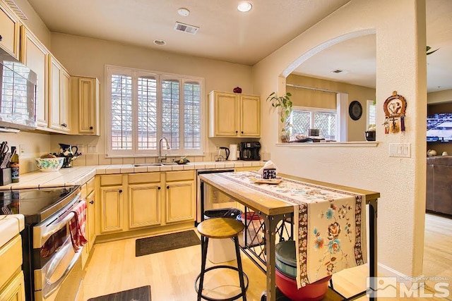 2078 Tivoli, Sparks, NV 89434 - kitchen with a sink, tile counters, appliances with stainless steel finishes, light wood-type flooring, and arched walkways