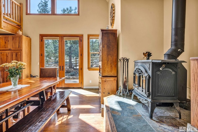 16375 Callahan Rd, Reno, NV 89511 - dining space featuring a wood stove, wood finished floors, a towering ceiling, baseboards, and french doors