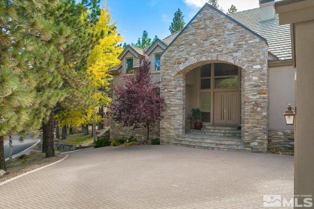 5680 Lausanne Dr, Reno, NV 89511 - doorway to property featuring stone siding, stucco siding, a chimney, and a high end roof