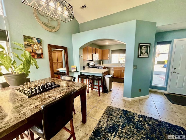 3131 Winter Rose Cir, Reno, NV 89502 - dining area with arched walkways, light tile patterned floors, high vaulted ceiling, and baseboards