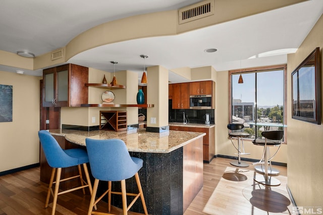 280 Island Ave Apt 802, Reno, NV 89501 - kitchen with open shelves, light wood-style floors, a peninsula, brown cabinets, and a breakfast bar area