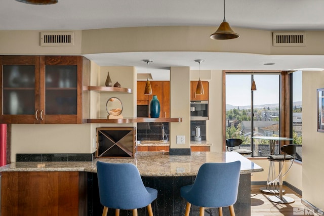 280 Island Ave Apt 802, Reno, NV 89501 - kitchen with brown cabinetry, light stone counters, pendant lighting, and a kitchen bar