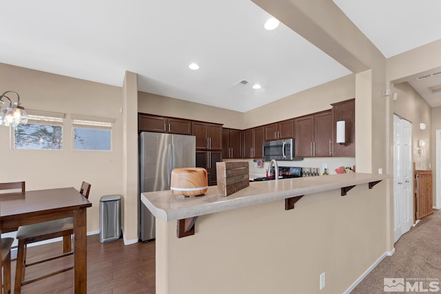 5310 Village Meadows Dr, Sparks, NV 89436 - kitchen with stainless steel appliances, a breakfast bar area, dark brown cabinets, light countertops, and recessed lighting