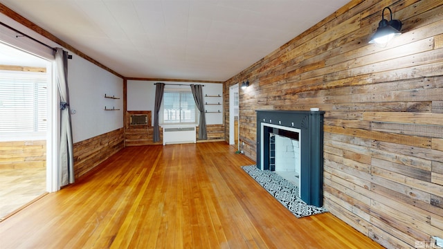 136 W First St, Winnemucca, NV 89445 - unfurnished living room featuring radiator, wooden walls, a tiled fireplace, wood finished floors, and a wainscoted wall