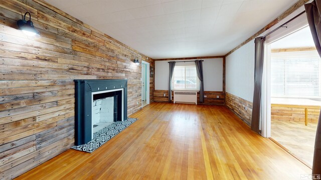 136 W First St, Winnemucca, NV 89445 - unfurnished living room featuring radiator heating unit, wood walls, light wood finished floors, and a fireplace