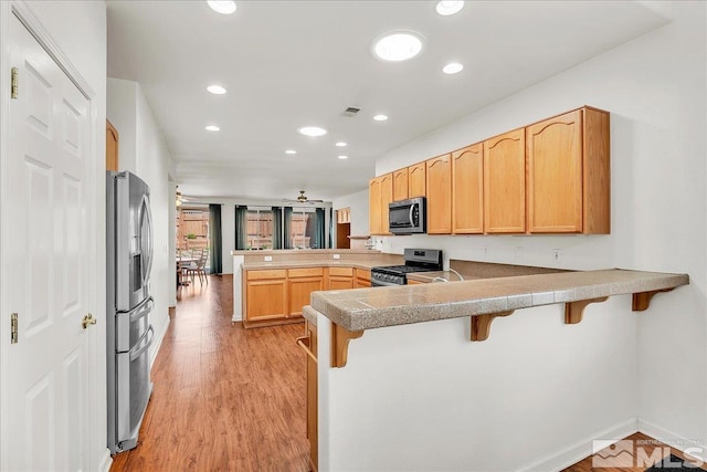 2140 Avella Dr, Sparks, NV 89434 - kitchen featuring appliances with stainless steel finishes, a peninsula, a kitchen breakfast bar, light wood-style flooring, and recessed lighting