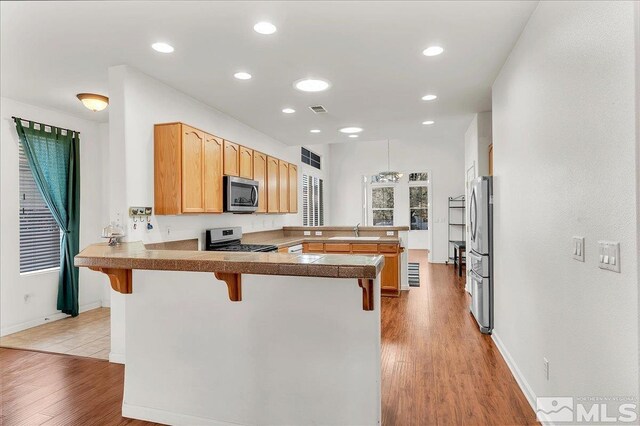 2140 Avella Dr, Sparks, NV 89434 - kitchen featuring stainless steel appliances, a peninsula, light wood-style floors, a kitchen breakfast bar, and a sink