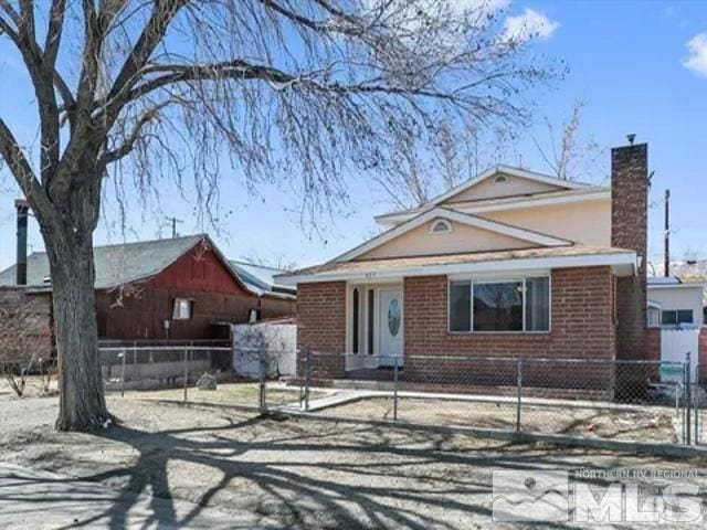 427 D St, Hawthorne, NV 89415 - view of front of home featuring a chimney, brick siding, and a fenced front yard