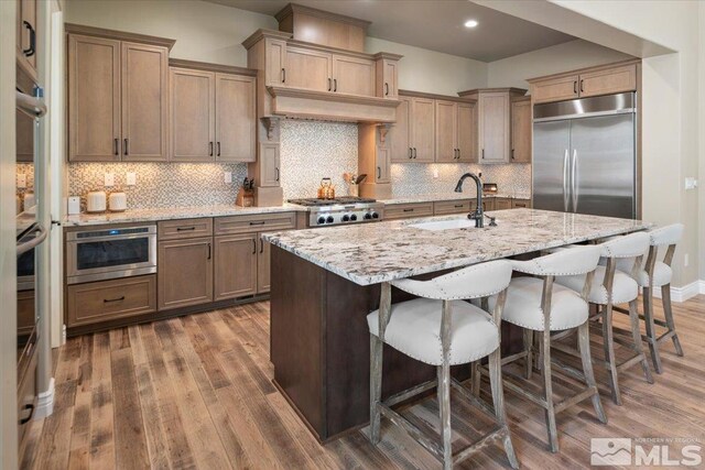 20605 Parc Foret Dr, Reno, NV 89511 - kitchen featuring a sink, stainless steel appliances, wood finished floors, light stone counters, and decorative backsplash