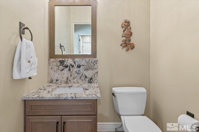 20605 Parc Foret Dr, Reno, NV 89511 - bathroom with toilet, vanity, baseboards, and decorative backsplash