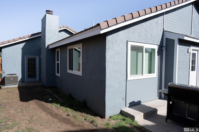 4806 Lincoln Ct, Carson City, NV 89706 - view of home's exterior featuring stucco siding, central AC, a tile roof, and a chimney