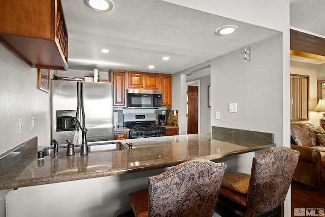 759 Boulder Ct Unit M, Stateline, NV 89449 - kitchen featuring appliances with stainless steel finishes, dark stone countertops, brown cabinets, a peninsula, and recessed lighting