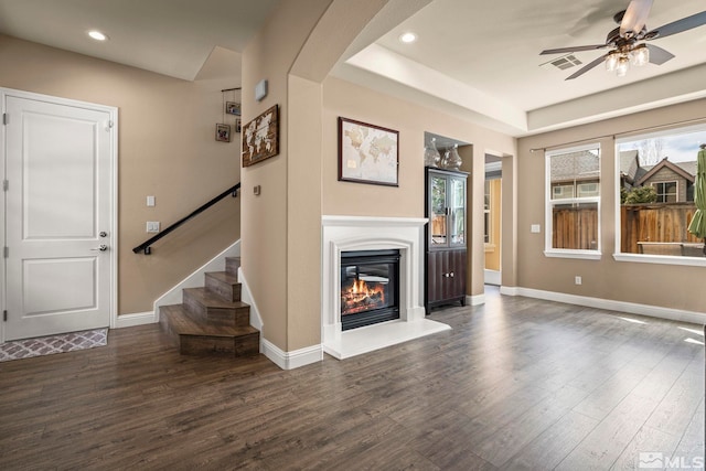 unfurnished living room featuring wood finished floors, a ceiling fan, a glass covered fireplace, stairway, and recessed lighting