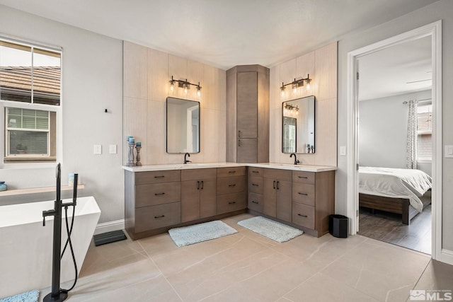 ensuite bathroom featuring a freestanding tub, vanity, tile patterned flooring, and baseboards