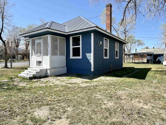295 Apache St, Imlay, NV 89418 - view of side of home with a chimney, a sunroom, a yard, and metal roof